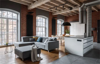 A união de diferentes ambientes é bem comum no estilo de decoração industrial, como nessa foto onde a sala de jantar e a sala de estar estão juntas